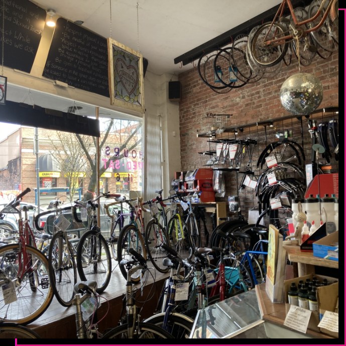 Inside Our Community Bikes: rows of refurbished bikes, a brick wall of parts, wheels and a disco ball hanging from the ceiling