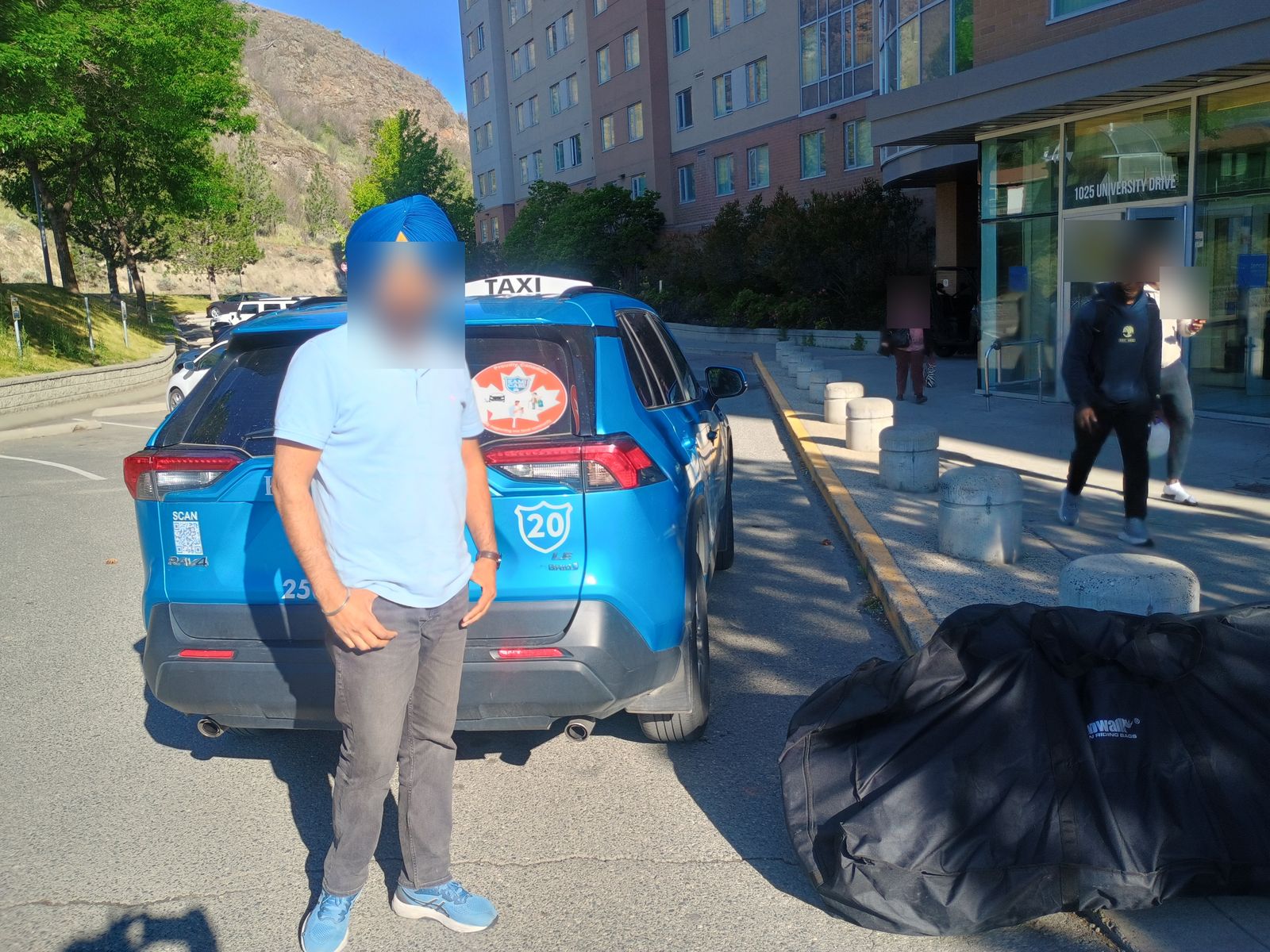 Taxi driver standing beside a Kami Cabs RAV4, bike bag in the foreground