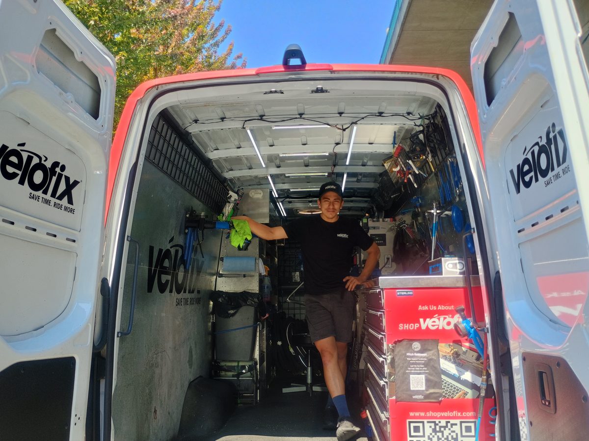 Mitchell standing in the back of the velofix van, surrounded by tools and parts drawers