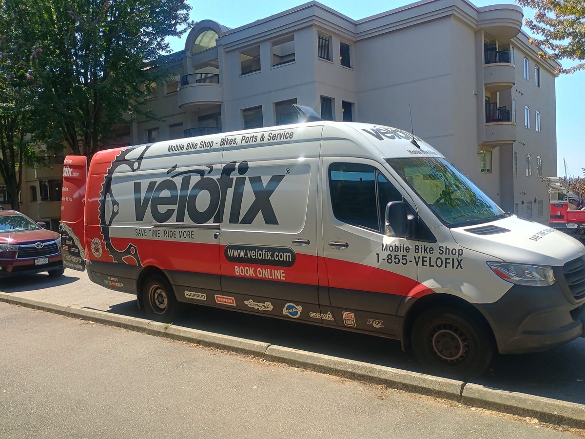Velofix Sprinter van parked at a curb, wrapped in a giant chainring graphic